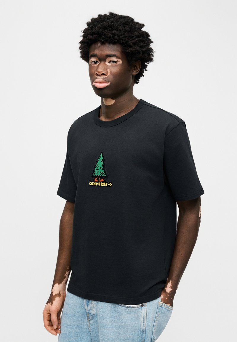 Maglietta nera in cotone con albero verde e scritta "Converse" multicolore ricamata sul davanti. Tessuto morbido, maniche corte.