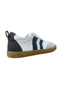 Zapatilla de cuero blanca y negra con una superficie texturizada, que cuenta con una suela de goma y un diseño de franjas con borde ondulado, cierre de cordones y bucle trasero.