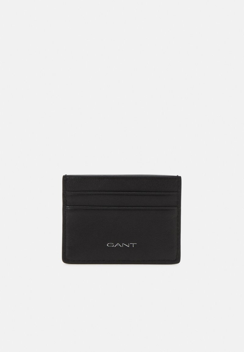 Cardholder din piele neagră cu patru sloturi pentru carduri, textură netedă și logo GANT embosat pe partea din față. Design simplu, rectangular.