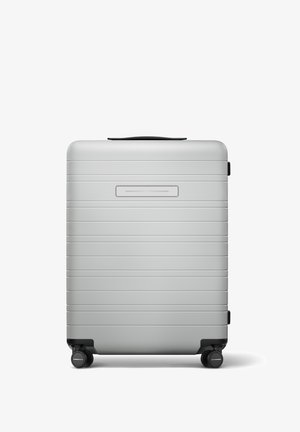 Silberner Hartschalenkoffer mit horizontalen Rillen, einem versenkten Griff, vier schwarzen Spinner-Rädern und einem Namensschildslot.