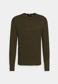 Sweter z dzianiny w oliwkowym kolorze, z długimi rękawami, okrągłym dekoltem, ściągaczami na mankietach oraz małym logo na piersi. Gładka faktura.