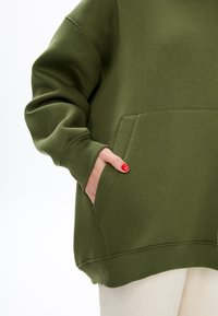 Groene katoenen sweatshirt met een losse pasvorm, geribde manchetten en een voorzak. Gladde textuur met een rechte zoom aan de onderkant.