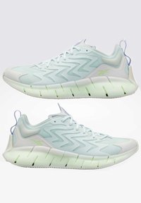 Paire de chaussures de sport bleu clair et blanc avec motifs en zigzag et semelles épaisses segmentées, vues de côté sur un fond uni.