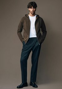 Brązowy polar z zamkiem, biała koszula, ciemne spodnie i czarne buty. Miękka tekstura, nowoczesny krój, casualowy styl o minimalistycznym designie.
