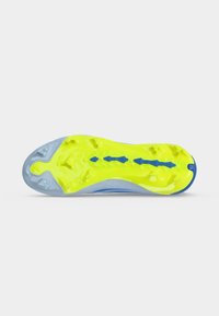 Semelle d'une chaussure de sport avec des crampons jaunes et bleus, conçue pour l'adhérence sur des surfaces de sol souple.