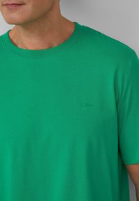 Zielona koszulka z okrągłym dekoltem, wykonana z gładkiej bawełny. Posiada subtelne logo s.Oliver wytłoczone na lewej piersi. Krótkie rękawy.