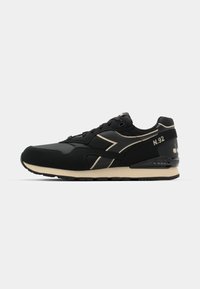 Black sneaker with a mix of matte and perforated textures, featuring a contrasting beige sole and gold accents, including "N.92" detail.