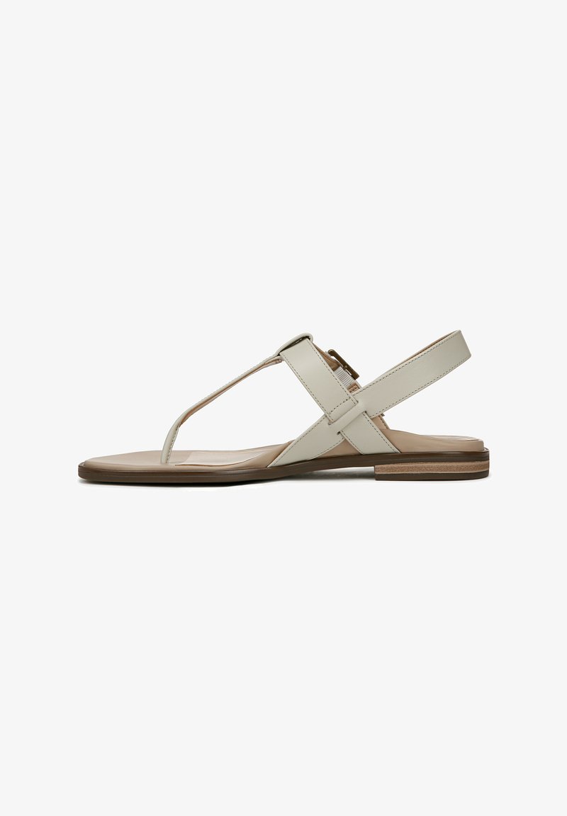 Light beige flat sandals featuring a T-strap design, cross straps, and a minimalistic sole with a subtle wood accent.