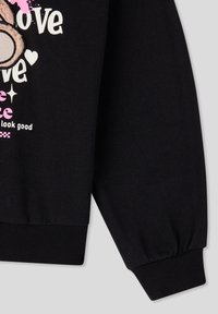 Felpa nera con polsini a costine, design grafico con testo bianco e rosa e un accento in peluche che somiglia a una mano.