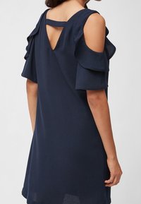 Laivastonsininen mekko, jossa on lyhyet, röyhelömäiset hihat, avara selkäosa ja rento istuvuus sileällä pinnalla.