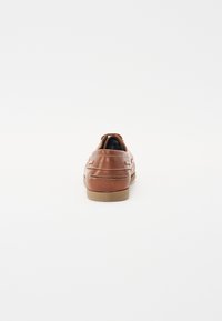 Braune Lederloafer mit weißer Naht und Gummisohle, von hinten auf weißem Hintergrund betrachtet.