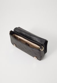 Schwarze synthetische Handtasche mit strukturiertem Äußeren, goldfarbenen Beschlägen und beigem Innenraum mit Fächern. Offenes Design zeigt die Innendetails.