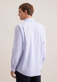 Camicia azzurro chiaro a maniche lunghe con un piccolo motivo geometrico, polsini con bottoni, colletto classico e design del retro con spalla dritta.