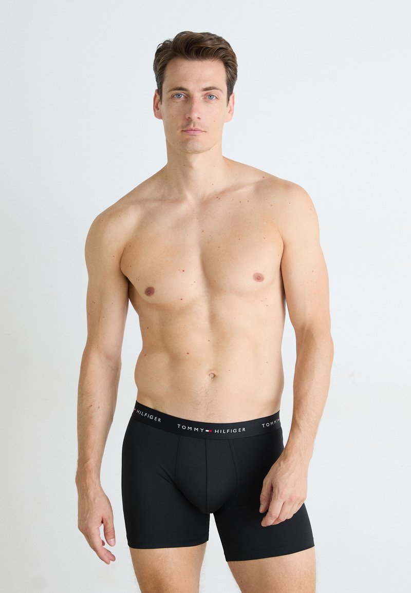 Schwarze Boxershorts für Herren mit enganliegendem Schnitt, aus glattem Stoff gefertigt. Verfügt über einen elastischen Bund mit Markenlogo und dem Text "TOMMY HILFIGER".