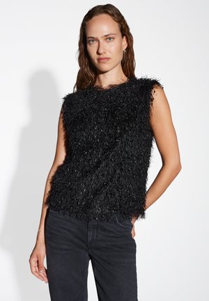 Zwarte mouwloze top met een gestructureerd, fluffy ontwerp; gemaakt van een zachte stof, heeft een losse pasvorm en een ronde halslijn. Gecombineerd met donkere jeans.