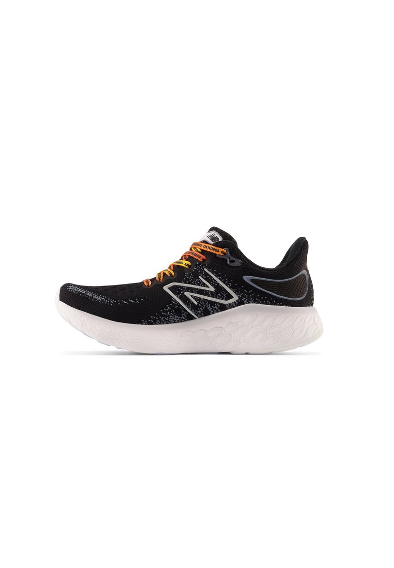 Zapatilla deportiva negra con parte superior texturizada, que presenta detalles y cordones en naranja. Suela blanca gruesa con un diseño estampado.
