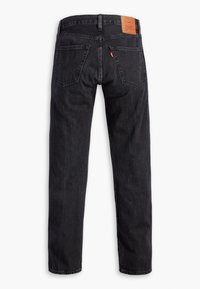 Jean en denim noir avec jambes droites, deux poches arrière, passants de ceinture, un écusson en cuir marron de la marque et une petite étiquette en tissu rouge sur la poche droite.