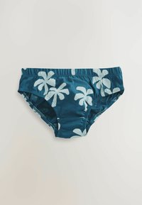 Svømmebukser i mørk teal stof med hvidt palmebladsmønster, der har en elastisk talje og syede kanter for komfort.