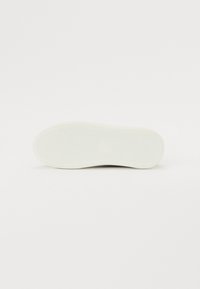 Vit sneakersula med texturerad gummi, rundad form och tydligt mönster. Ren design som passar för avslappnad användning.