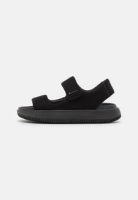 Sandales noires au toucher lisse et velouté, dotées d'une large sangle avec fermeture Velcro et d'une semelle épaisse et rainurée pour une meilleure traction.