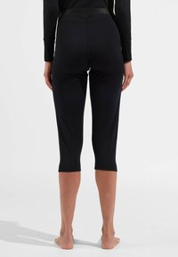 Leggings noirs trois quarts en tissu lisse avec une taille ajustée et des coutures discrètes, se terminant juste en dessous des mollets.