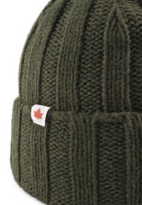 Cappello a maglia di colore verde scuro con texture a coste. Presenta un piccolo etichetta bianca con un accento a foglia d'acero rossa.