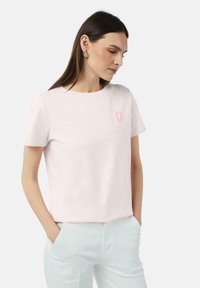 Hellrosa Baumwoll-T-Shirt mit rundem Ausschnitt und kurzen Ärmeln. Verfügt über ein kleines gesticktes Logo auf der linken Brust. Glatte Textur.