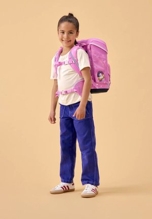 Sac à dos rose avec un motif d'étoiles, présentant un graphique de personnage, des bretelles réglables et une base noire. L'enfant porte un haut blanc et un pantalon bleu.