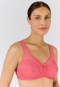 Sujetador rosa con detalles de encaje y un acabado mate suave. Presenta un escote en forma de V y tirantes ajustables. Acento de lazo notable en la parte delantera central.