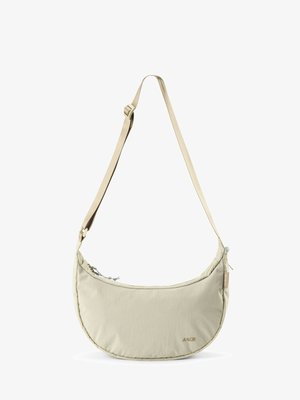 Sac bandoulière beige en forme de croissant avec sangle ajustable, fermeture éclair et petit logo de la marque en bas à droite sur le devant.