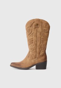 Helle Wildlederschuhe bis zur Wade im Western-Stil mit gestickten Dekorationsmustern und gestapeltem Absatz auf weißem Hintergrund.