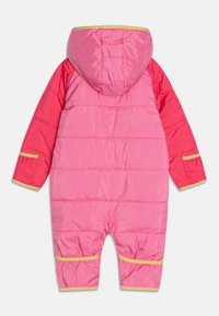 Różowy kombinezon puchowy z kapturem, z kontrastującymi czerwonymi rękawami. Ozdobiony żółtymi wykończeniami i poziomym przeszyciem pikowanym na całej powierzchni.