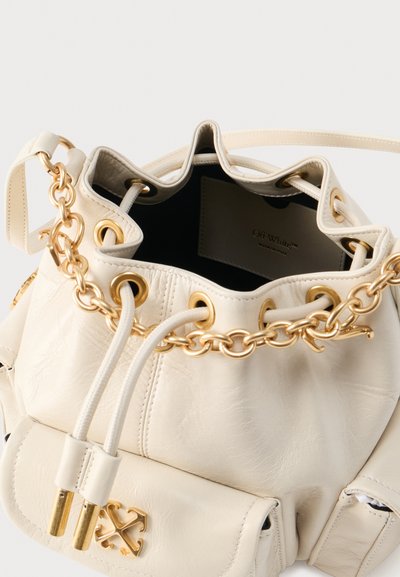 Κρεμ δερμάτινη τσάντα τύπου πουγκί με χρυσή αλυσίδα και μεταλλικά δαχτυλίδια, κλείσιμο με κορδόνι, μπροστινή τσέπη και λογότυπο Off-White στο εσωτερικό ύφασμα.