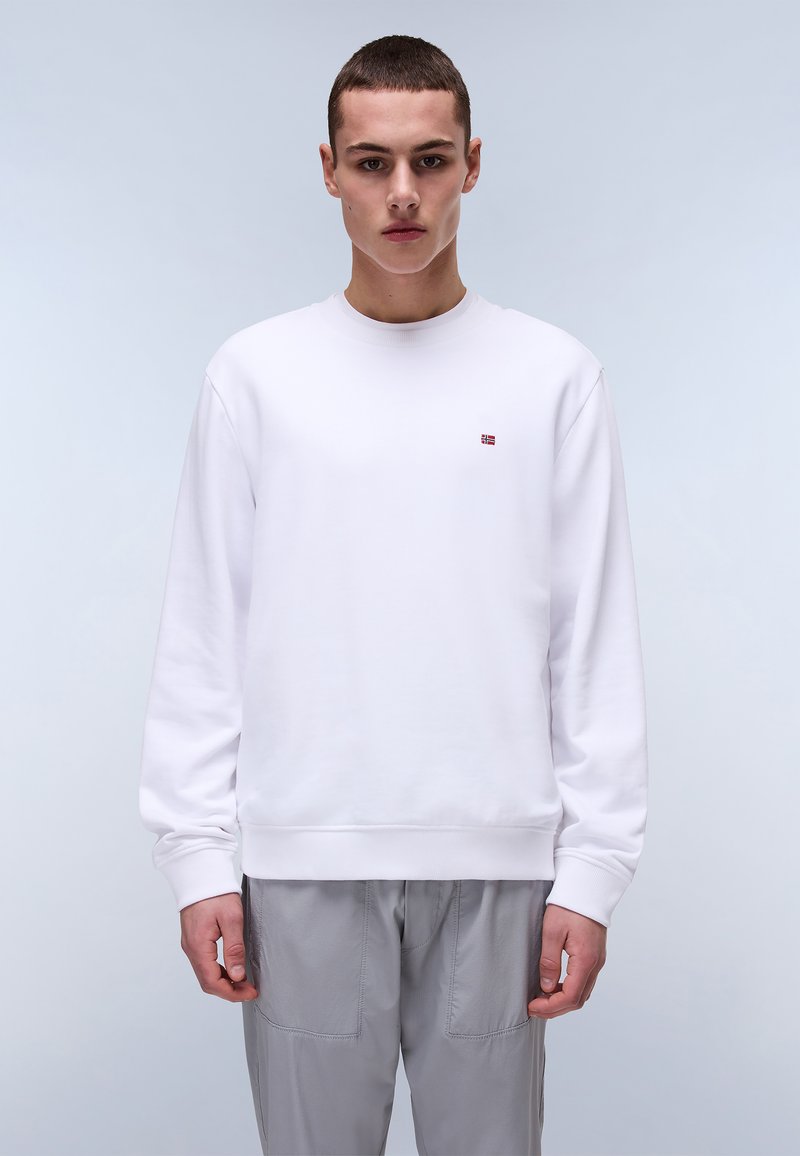Hvid sweatshirt, rund hals, ribbede manchetter og kant, lille logo på brystet, glat tekstureret stof. Bæres med grå, løst siddende bukser.