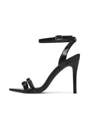 Sandale noire à talon haut avec un bout pointu, des straps élégants avec boucles et une sangle à la cheville. Texture en cuir lisse et poli.