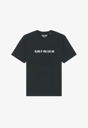 T-shirt in cotone nero con maniche corte, colletto a girocollo e testo bianco audace: "Fai un blink se ti piaccio" sul petto.