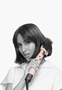 Hårstylingsverktyg med en rosa och vit design, borsttillbehör och kontrollknappar. Strukturerat grepp och flexibel sladd ingår.