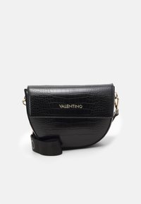 Schwarze Leder-Crossbody-Tasche mit Krokodilstruktur, kurvenförmigem Design, goldenen Logos und einem abnehmbaren Schulterband aus Stoff.