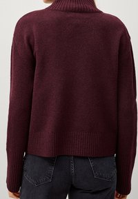 Pull en tricot bordeaux à col montant, poignets et taille côtelés, présentant une coupe décontractée et un tissu texturé.