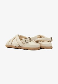 Beige sandalen met een kruisbandontwerp, gemaakt van zacht materiaal. Voorzien van een gesp op een verstelbare band en een gestructureerde rubberen zool.