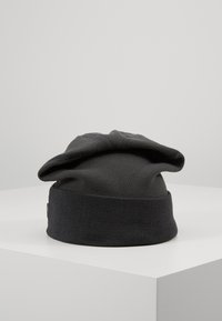 Beanie in maglia nera con risvolto a coste, caratterizzato da una parte superiore morbida e leggermente cadente, realizzato in un tessuto liscio e testurizzato.