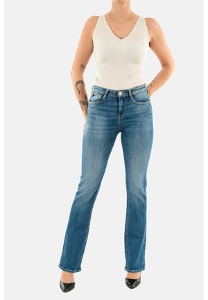 Top sin mangas de canalé en color blanco roto con escote en V, combinado con jeans de tiro medio de pierna recta en azul con un acabado desteñido y detalles de costura sutiles.