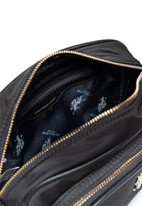 Borsa nera con cerniera, dal rivestimento liscio, interiormente presenta un tessuto scuro con un motivo a logo blu ripetuto e numerosi scomparti.