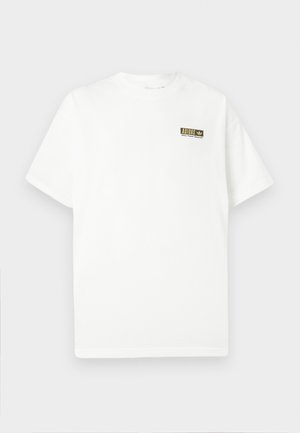 Valge lühikeste varrukatega T-särk, millel on vasakul rinnal väike must ja kuldne Adidas logo ning tekst.