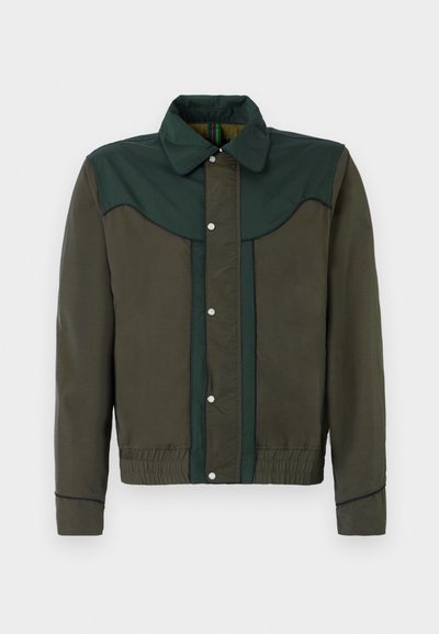 Zelen in rjav plašč z zapenjanjem na gumb, ovratnikom ter elastiko na manšetah in robu. Ima kontrastne barvne panele in subtilno teksturo.