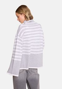 Grå og hvit stripete genser med høy krage, oversized silhuett og vide ermer i et mykt, teksturert strikket stoff.