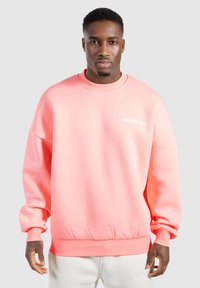 Sudadera rosa con cuello redondo y puños acanalados. Presenta el texto "SMILODOX Ltd." en blanco, hecha de una tela suave con un ajuste relajado.