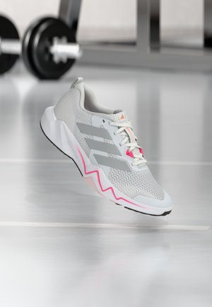 Gray athletic shoe with a textured mesh upper, white sole, pink accents, and three parallel stripes on the side. Zigzag design at the sole.