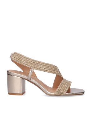 Sandalia de mujer con tacón cuadrado metálico dorado, puntera abierta y tiras cruzadas con cuentas, además de una correa trasera en el tobillo.