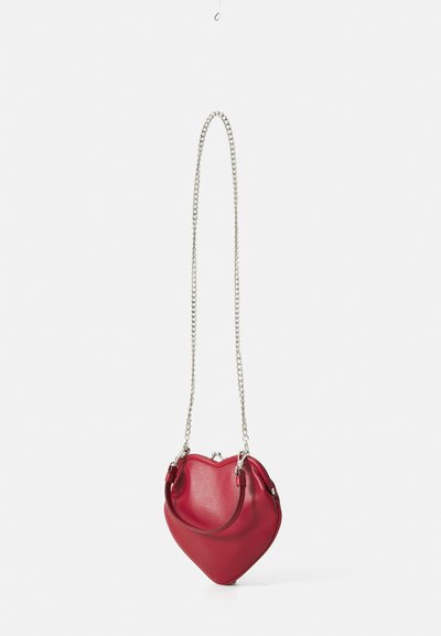Red leather handbag in a heart shape with a textured surface, featuring a silver chain shoulder strap and small top handles.
